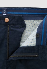 Donkerblauwe broek met een ruitpatroon; voorzien van een koperen knoop, een gouden rits en een lichtblauwe stof met patroon aan de binnenkant.