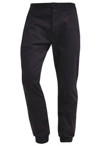 Pantalon noir fuselé avec poignets élastiques et fermeture à bouton et glissière à l'avant, présenté sur un fond blanc.