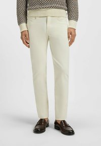 Ljust beige bomullschinos med slim fit, med framfickor och sydda detaljer, kombinerade med mörkbruna loafers.