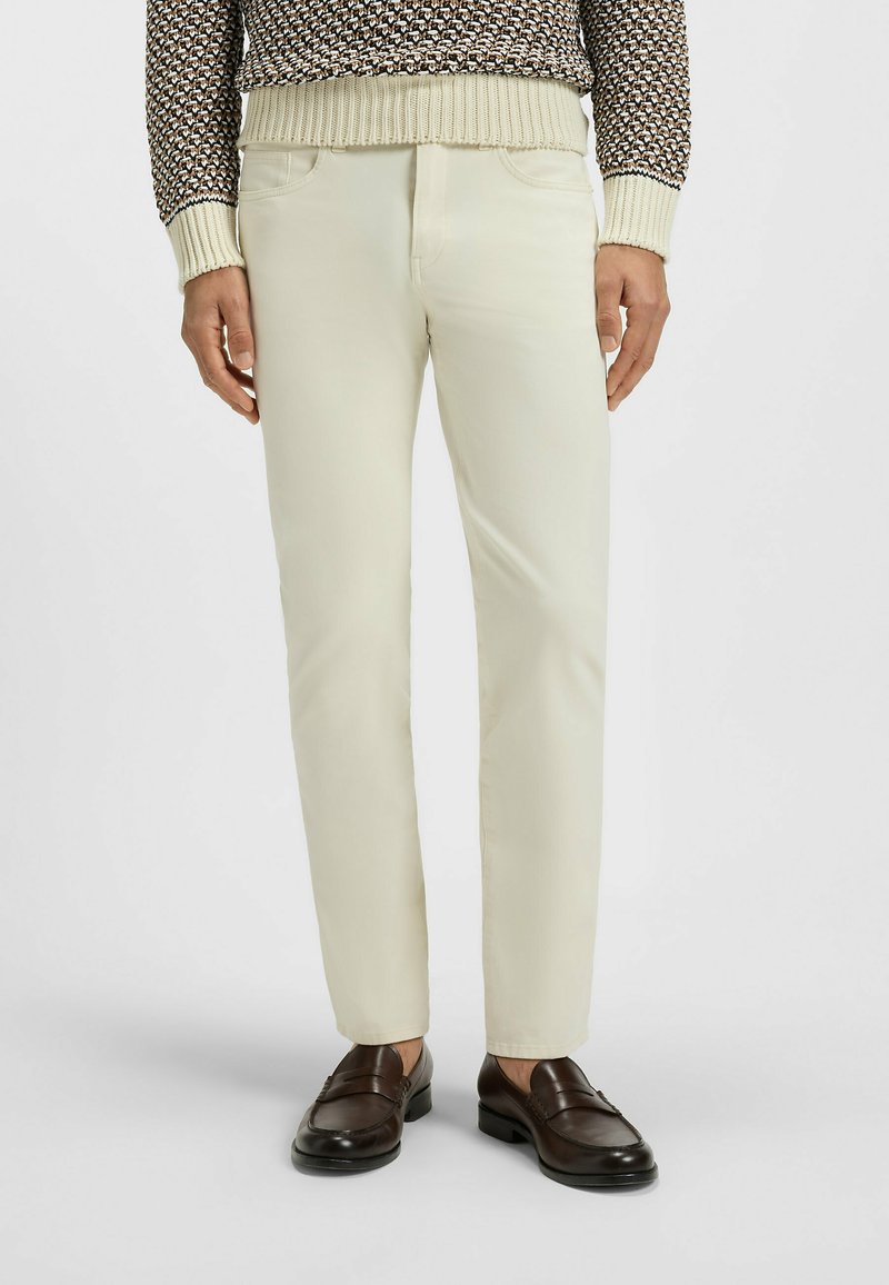 Ljust beige bomullschinos med slim fit, med framfickor och sydda detaljer, kombinerade med mörkbruna loafers.