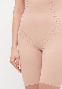 Nude visoko pasni bodi kratke hlače iz gladkega, raztegljivega materiala z perforiranimi detajli ob šivih in prilagojeno obliko.