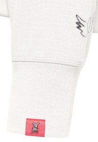 Lichtgrijze sweatermouw met een gestructureerde afwerking, voorzien van een subtiele grijze tekening en een klein rood etiket met een geborduurd hondenlogo.
