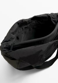 Black fabric bag with a soft texture, featuring a zippered main compartment and additional zippered pocket on the interior.