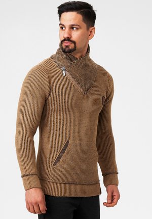 Brun striktrøje med høj krave, detaljeret med zip-krave, tekstureret ribbing og en frontlomme. Fremstillet af blødt stof.