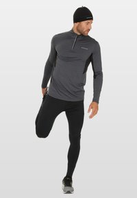 Thermisch hardloopsweater in donkergrijs met een kwart-rits, lange mouwen en zwarte zijpanelen. Gecombineerd met zwarte aansluitende legging.