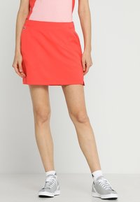 Różowy szort wykonany z lekkiego materiału, o prostym kroju, z bocznymi kieszeniami i gładką fakturą. W połączeniu z szarymi butami sportowymi.