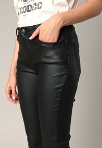 Zwarte nep leren skinny broeken met een hoge taille, voorzakken en een strakke textuur. Kenmerken zijn stiksels en een gladde afwerking.