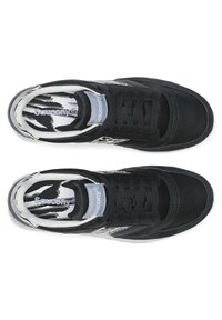 Un paio di sneakers nere Saucony con accenti bianchi e grigi, chiusura con lacci e solette a motivo bianco e nero viste dall'alto.