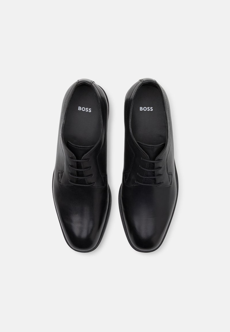 Chaussures habillées en cuir noir avec une texture lisse, un design à lacets et un bout arrondi. Le logo "BOSS" apparaît sur les semelles intérieures.