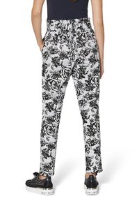 Schwarz-weiße Blumenmuster-Hosen mit elastischem Bund, geraden Beinen und Seitentaschen, kombiniert mit schwarzen Schuhen.