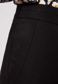 Svarta skräddarsydda byxor med en slät textur, rak passform och diskreta sidfickor, samt en accentuerad söm framtill.