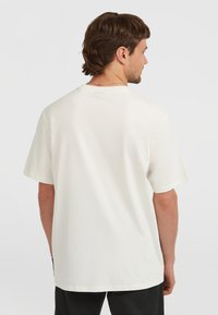 T-shirt bianco in cotone con maniche corte e colletto a giro, caratterizzato da un design semplice e una vestibilità comoda. Minima brandizzazione visibile sul retro.