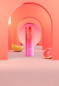 KIKO Power Shake Pearly Magic Serum in een roze fles, met een spraymond, tegen een perzik achtergrond met sinaasappel- en grapefruitplakken.