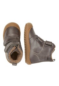 Botas de tobillo marrones de cuero con dos correas de velcro, forro de piel suave y suela de goma con textura para mejorar el agarre.