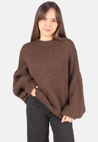 Brauner gestrickter Pullover mit lockerem Sitz, gerippter Struktur und rundem Ausschnitt. Verfügt über breite Ärmel und eine entspannte Silhouette.