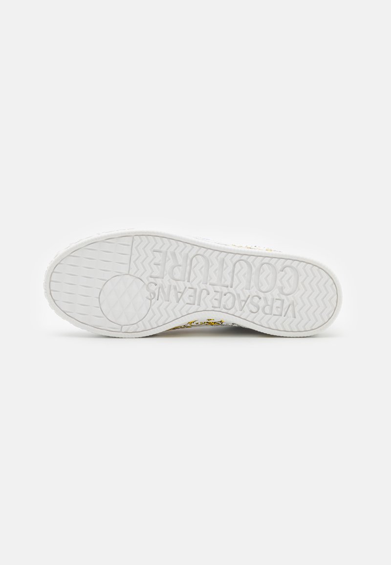 Suola di sneaker bianca con motivo di grip testurizzato. Presenta il logo del brand in rilievo e elementi di design gialli e neri lungo i lati.
