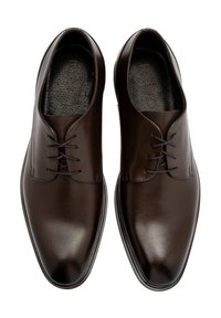 Zapatos de vestir de cuero marrón con un acabado suave, presentando un perfil bajo, punteras redondeadas y cordones delgados para un cierre seguro.
