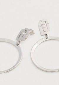 Orecchini a cerchio in argento con perni geometrici a forma di quadrato, ognuno dei quali presenta un design a intaglio e il nome del marchio "Liu Jo" inciso su uno sfondo chiaro.