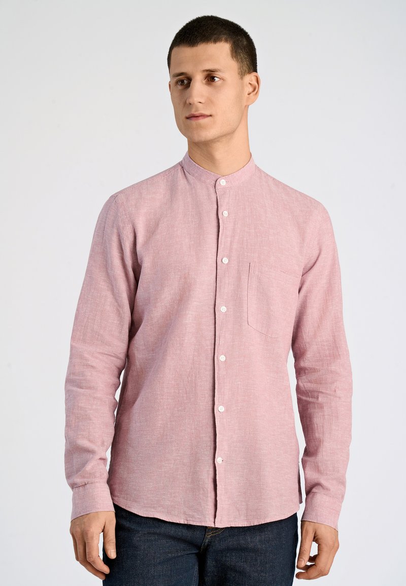 Camicia rosa chiaro a maniche lunghe con colletto alla cinese, taschino frontale e chiusura con bottoni sul davanti, realizzata in un tessuto testurizzato.