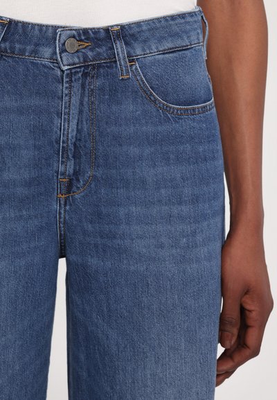 Denim jeans in a medium wash with a straight-cut design. Features include a button closure, five pockets, and contrast stitching.
