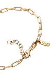 Guldtonat kedja armband med avlånga länkar, en hänglås, och en liten tagg med "emoji" graverad. Slät yta och blanka finish.