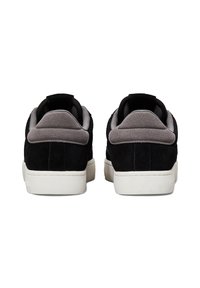 Schwarze und graue Wildledersneaker mit einer strukturierten Oberfläche, ausgestattet mit einer weißen Sohle und einem gepolsterten Schaft für Komfort.