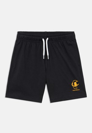 Mustad elastse vöökohaga lühikesed püksid valge nööriga ja väikese kollase spordirõivaste logoga vasakul säärel, laotatud valgel taustal.