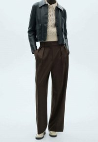 Skórzana kurtka cropped, beżowy sweter o fakturze, brązowe spodnie plisowane i kremowe buty. Neutralne kolory, dopasowany krój, czyste linie.