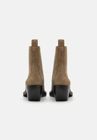 Hnědé semišové kotníkové boty s černým zvýšeným podpatkem a elastickými bočními panely. Design je elegantní s hladkou texturou a minimalistickou siluetou.