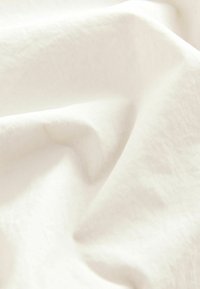 Tissu blanc doux et lisse avec de légers plis et des détails subtils de texture sous la lumière naturelle.