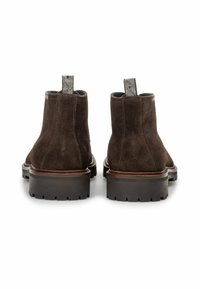 Braune Wildleder-Stiefeletten mit strukturierten Zuglaschen und robusten gummierten Sohlen. Mit einer glatten Lederverzierung entlang der oberen Kante.