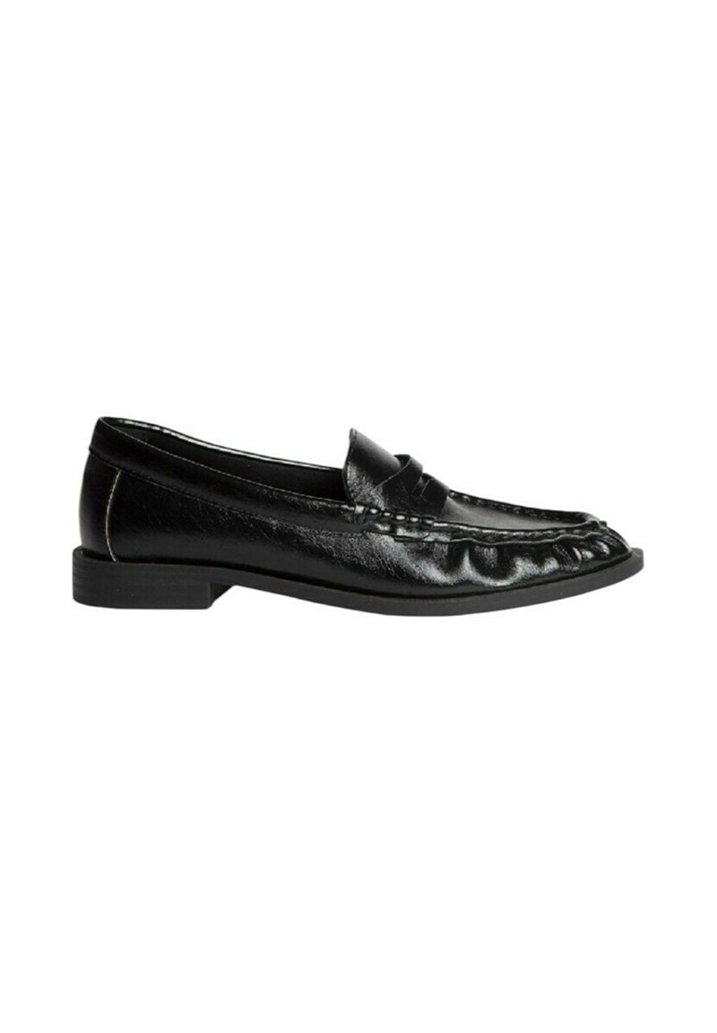 Mocasines de cuero negro con punta redondeada, detalles fruncidos en la parte frontal y una suela de goma texturizada y baja.