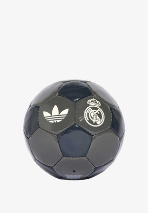 Balón de fútbol gris y azul marino hecho de cuero brillante. Presenta el logo blanco de Adidas y el emblema del Real Madrid. Paneles hexagonales con textura suave.
