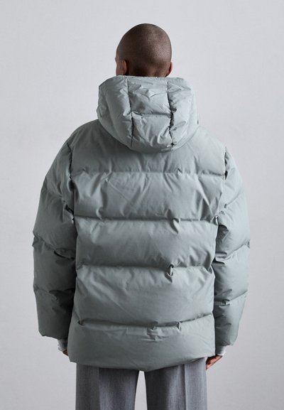 Puffer jacket in light gray, featuring a hood, stitched sections, and a relaxed fit. Smooth, shiny texture with no visible hardware.