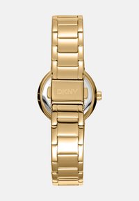 Goldene Metalluhr mit einem glatten, verknüpften Armbandstil. Runder Ziffernblatt mit silbernen Akzenten und DKNY-Logo auf der Rückseite. Polierte Oberfläche.