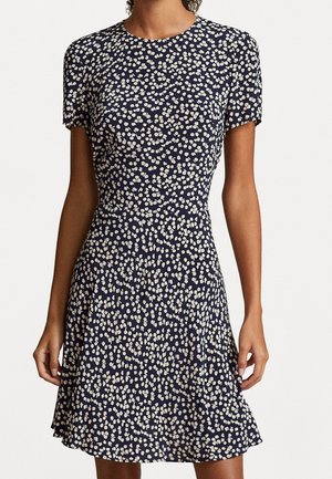 Marineblauwe jurk met bloemenmotief en korte mouwen, voorzien van een getailleerd lijfje en een uitlopende rok, versierd met witte bladachtige patronen over het geheel.