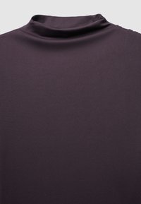 Haut à col roulé violet foncé en tissu lisse et extensible, à coupe ajustée et col montant, présentant une texture unie sans motifs.