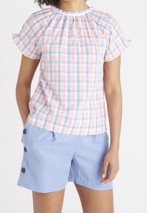 Bluzka w pastelową kratę z krótkim rękawem i marszczonym dekoltem, zestawiona z niebieskimi szortami z ozdobnymi guzikami po bokach.