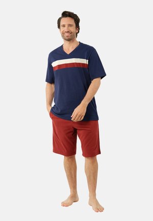 T-shirt en V bleu marine avec un design à rayures blanches et rouges, associé à un short rouge. L'ensemble présente une coupe décontractée et un tissu doux.