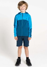 Blaues Zip-Up-Jacke mit Kapuze und dunkleren blauen Shorts. Getragen mit schwarzen Wanderschuhen. Glatte Textur, athletic Fit und funktionales Design.