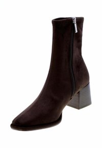 Stivaletto in suede marrone con punta affusolata, cerniera laterale e tacco quadrato chunky. La gamba è elegante e liscia, offrendo una silhouette aderente.