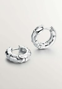 Pendientes de aro huecos en plata pulida con un diseño inspirado en el bambú. Presentan una textura suave y brillante y formas redondeadas.