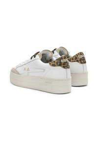 Sneakers bianchi in pelle con una punta beige texturizzata, dettagli leopardati sul tallone e lacci neri in contrasto. Suola spessa bianca.