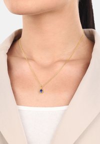 Collana in oro con un ciondolo ovale in pietra blu. La catena è fine e delicata, mentre il colore vivace del ciondolo è ben messo in risalto.