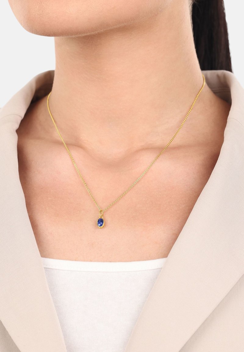 Collana in oro con un ciondolo ovale in pietra blu. La catena è fine e delicata, mentre il colore vivace del ciondolo è ben messo in risalto.