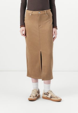 Brun suedet midi skjørt med frontspalte, med kontraststing og fem-lomme design. Sett sammen med sneakers med dyreprint og hvite sokker.
