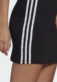 Czarna bawełniana sukienka z trzema pionowymi białymi paskami po boku, o gładkiej fakturze i dopasowanym kroju.