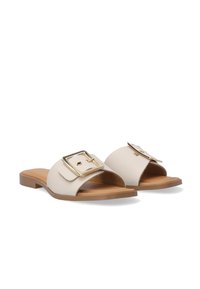 Lysbeige slidesandaler lavet af tekstureret læder, med en stor metalbuckle som accent. Flad sål med en glat brun inderside.
