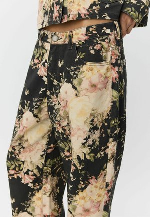 Floral pattern trousers in black, featuring pink and yellow flowers. Made from denim with side pockets and a zip fly.