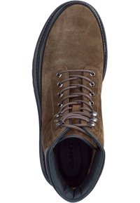 Bruine suède laars met ronde neus, zes metalen oogjes, contrasterende donkere zool en gewatteerde kraag. Logo zichtbaar op de binnenzool.